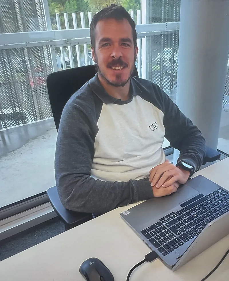 Portrait d’Unai, souriant à son bureau, devant son ordinateur portable